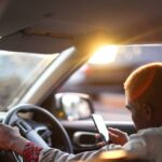 Egy utas ül az autóban, telefonján az Uber alkalmazást használja.