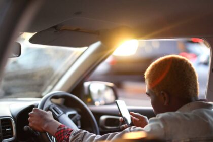 Egy utas ül az autóban, telefonján az Uber alkalmazást használja.