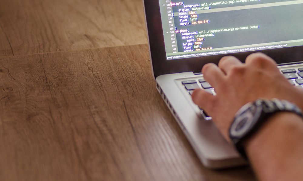 Egy kéz, amely egy laptop billentyűzetén kódot ír, modern frontend fejlesztés közben.