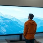 Felhasználó egy nagy kijelzőn gyönyörködik a hegyek panorámájában